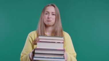 Tembel liseli ya da öğrenci yeşil arka plan üzerine kitap ev ödevi miktarından memnun değil. Hoşnutsuzluk içindeki bir kız, çalışmalardan bıkmış, hayal kırıklığına uğramış. Yüksek kalite 4k