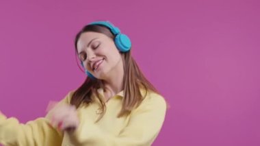 Mutlu kadın kafayı bulur, müzik dinler, pembe stüdyo arka planında kulaklıklarla dans etmekten zevk alır. Radyo, kablosuz modern ses teknolojisi, çevrimiçi çalar. Yüksek kalite 4k