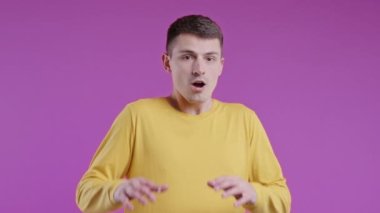 Şok olmuş korkmuş bir adam bir şeyden korkuyor ve pembe arka planda korku dolu büyük gözlerle kameraya bakıyor. Fobi, sorun, panik konsepti. Yüksek kalite 4k