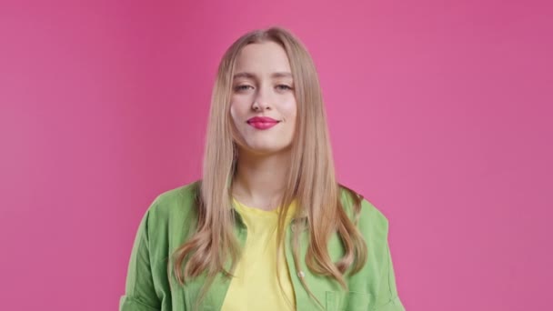 唇に指を持つ美しい女性の笑顔 ピンクのスタジオの背景 ゴシップの概念のジェスチャーでかなりの女性 高品質4K — ストック動画