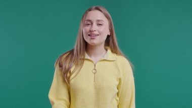 Gülümseyen güzel bir kadın, parmaklarını dudaklarında tutuyor, mavi stüdyo arka planı. Şşş, sır, sessizlik, komplo, dedikodu konsepti olan hoş bir bayan. Yüksek kalite 4k