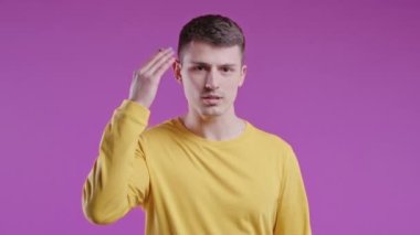 Sinirli genç adam kamerayı gösteriyor ve aptalca bir hareket yapıyor. Deli misin diye soruyorum. Kavgacı adam pembe arka planda izole edilmiş. Öfkeli ifade, birini suçlamak..