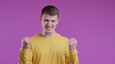 Genç adam zafer gösteriyor evet evet zafer jesti, başarıya ulaştı, hedeflere ulaştı. Mutlu, mutlu, şaşırmış, pembe arka plandaki mutlu adam. Büyük ikramiye konsepti. Yüksek kalite 4k