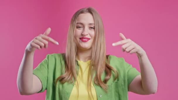 Ξανθιά Γυναίκα Δείχνει Κάτω Στην Περιοχή Της Διαφήμισης Ροζ Φόντο — Αρχείο Βίντεο