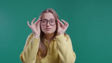 Güzel kadın gözlerine inanamıyor, gözlüklerini çıkarıp şaşı bakıyor çünkü mavi arka planda hiçbir şey göremiyor. Görme bozukluğu, görme bozukluğu. Uzun sarı saçlı genç bayan. 4k