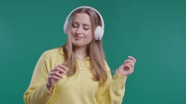 Mutlu kadın kafayı bulur, müzik dinler, mavi stüdyo arka planında kulaklıklarla dans etmekten zevk alır. Radyo, kablosuz modern ses teknolojisi, çevrimiçi çalar. Yüksek kalite 4k