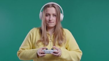 Sarışın, genç ve güzel bir kadın mavi stüdyo duvarında joystick ile TV 'de video oyunu oynuyor. Modern teknolojiyi kullanarak. 4k