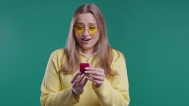 Güzel bir kadının mavi duvar arkasında elmas yüzük olan mücevher kutusu var. Gülümseyen bir kadın, nişanlı olduğu için mutlu, evlilik teklifi, Sevgililer Günü hediyesi. Yüksek kalite 4k