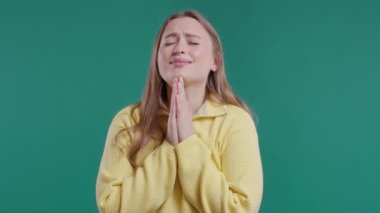 Genç bir kadın dua ediyor, özür diliyor, o suçlu. Mavi arka plan. Umut dolu dua eden kız, birinden arzularını tatmin etmesini ister, yardım ister. Yüksek kalite 4k