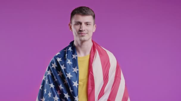 紫の背景に国旗を掲げた幸せな男 アメリカの愛国者 7月4日 独立記念日のお祝い アメリカ アメリカのバナー 高品質4K — ストック動画