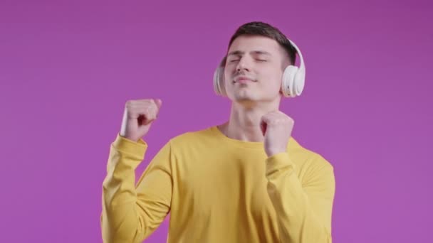 Позитивный Молодой Человек Слушает Музыку Наслаждается Танцами Наушниками Фоне Фиолетовой — стоковое видео