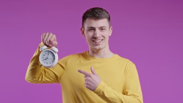 ピンクの背景に目覚まし時計を持つ幸せな男 正しい一日のルーチンは 瞬間に住んで 若者のすべての分に感謝します 高品質4K — ストック動画