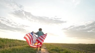 Sevimli küçük bir çocuk - Amerikan vatansever bir çocuk açık arazi yolunda ulusal bayrağıyla koşuyor. ABD, 4 Temmuz - Bağımsızlık Günü, Kutlama. ABD bayrağı, Gaziler Anıtı, Seçim, Amerika, İşçi Partisi