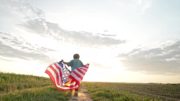 かわいい男の子 アメリカの愛国者の子供は オープンエリアの田舎道で国旗で走っています アメリカの旗 記念退役軍人 アメリカ — ストック動画
