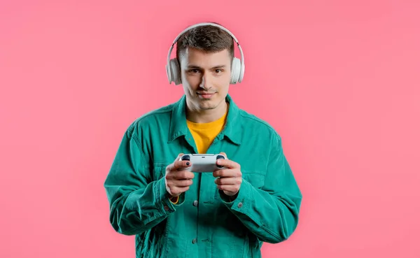 一个英俊的年轻人在电视上玩着令人兴奋的视频游戏 把操纵杆隔离在粉色工作室的背景下 使用现代技术 — 图库照片