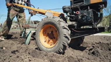 Çiftçi adam çalışıyor, bahçe çernozem tarlasını motorlu birim motoblock ile sürüyor. Yüksek kalite 4k görüntü