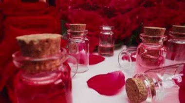 Şişelerde gül yağı. Sıvı aroma serumu üretiyor. Pipetten cam kutuya damlayan pembe damlalar. Soyut cilt bakım ürünleri. 4k görüntü.
