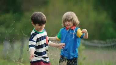 Küçük komik çocuklar samanla, otla oynuyorlar, kusuyorlar. Mutlu bir çocukluk. Gülümseyen çocuklar çimenleri biçtikten sonra eğleniyorlar.. 