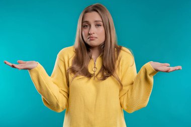 Confused pretty woman, shoulders up - can't help, makes gesture of I dont know. Difficult question, guilty reaction, puzzled stylish woman on blue background. High quality clipart