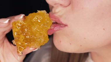 Balmumu bal peteğiyle bal yiyen bir kadın. Ağzını kapat. Sağlıklı yiyecekler, doğal tatlılar. Nefis bir geçmiş. Yüksek kalite 4k görüntü