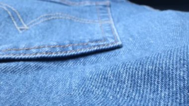 Makro mavi kot kumaş. Kot pantolonda profesyonel dikiş. Günlük kıyafet, yıpranmış kumaş. Tekstil giysilerinin klasik doku yüzeyi. Kaydırıcı Dolly son derece yakın çekim görüntüleri.
