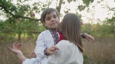 Annesiyle sevgi dolu oğlunun elma bahçesinde güneşli bir sahne. Güzel bir aile. Annesiyle birlikte 4 yaşında tatlı bir çocuk. Ebeveynlik, çocukluk, mutluluk, çocukların refahı kavramı.