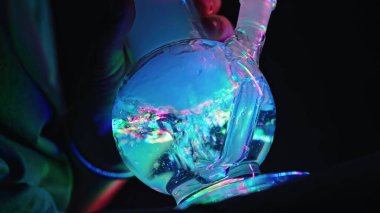 Tıbbi marihuana içmek, evdeki neon ışıkta cam su bongu içmek. Esrar. Yüksek kalite fotoğraf