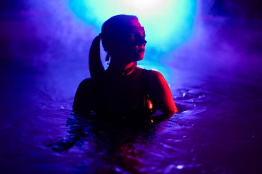 Deri DDSM maskeli, yüzme havuzunda dans eden, neon ışıklı, şehvetli bir kadın. Çekici piliç parti zamanı. Yetişkin eğlencesi, maskeli balo. Tehlikeli bir kadın. Yüksek kalite fotoğraf