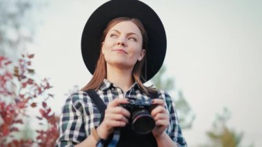 Sonbahar gökyüzü arka planında dijital kamerası olan genç hipster fotoğrafçı kadın portresi. Yüksek kalite 4k görüntü