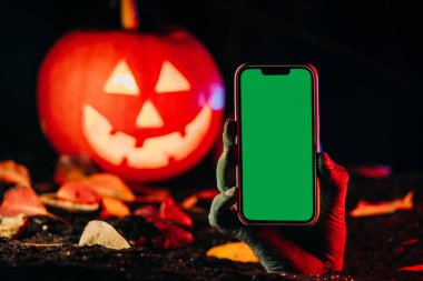 Akıllı telefonlu zombi eli. Ölümsüz, cadılar bayramı balkabağı, mobil operatör reklamı. Yeraltından korkunç bir manzara. Uzayı kopyala Yüksek kalite