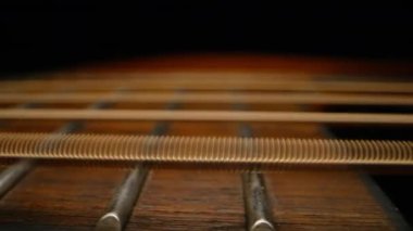 Titreşen akustik gitar telleri. Klasik müzik enstrümanı çalıyor. Ses dalgaları, tıngırdayan akorlar, ses rezonansı. Süper makro kaydırıcı. Yüksek kalite 4k görüntü