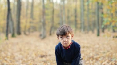 Parkta düşen portakal yapraklarıyla oynayan komik çocuklar kusuyor. Mutlu bir çocukluk. Gülümseyen çocuk altın ormanda eğleniyor..
