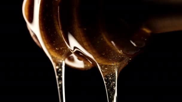 オーガニックハチミツは オリーブの木製ディッパースティックスプーン おいしいプロセスから流れます Apiary 養蜂コンセプトについて ドリッピング スローモーションで甘い液体の蜜を注ぐ 高品質の4K映像 — ストック動画