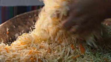 Kadın geleneksel Ukraynalı mayalanmış lahana ve havuçtan lahana salatası pişiriyor. Ailede doğranmış sebzeleri eski ahşap yalaklarda karıştırıyor. Yüksek kalite 4k görüntü