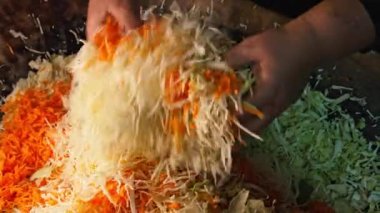 Kadın geleneksel Ukraynalı mayalanmış lahana ve havuçtan lahana salatası pişiriyor. Ailede doğranmış sebzeleri eski ahşap yalaklarda karıştırıyor. Yüksek kalite 4k görüntü