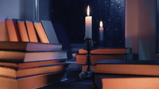 一堆堆堆放在木制窗台上的旧书 沐浴在柔和的烛光中 秋天的舒适气氛 蜡烛的燃烧 文学促销或平静的视觉叙事 秋天的雨天 — 图库视频影像