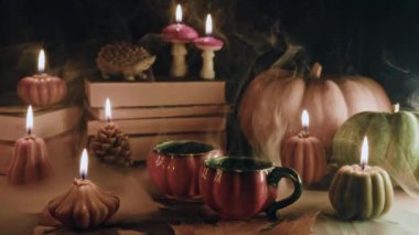 Balkabağı mumlarının arasında şirin çay fincanları. Sonbahar temalı içerik, kafe promosyonları ya da rahatlatıcı görsel hikaye anlatımı. Samimiyet, huzur ve davetkar atmosfer.. 