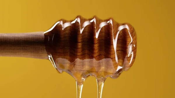 Organic honey flows from olive wood dipper stick spoon, tasty process. Apiary, beekeeping concept. Dripping, pouring sweet fluid nectar in slow motion. High quality 4k footage