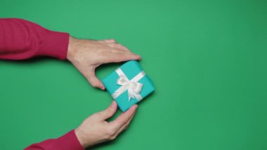 Erkekler ve kadınlar Noel hediyelerini yeşil arka planda alırlar. Üst düzey eller. Özgün ifadeler, şenlikli arka plan. Görsel hikaye anlatımı. Yüksek kalite 4k görüntü