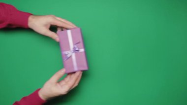 Erkekler ve kadınlar Noel hediyelerini yeşil arka planda alırlar. Üst düzey eller. Özgün ifadeler, şenlikli arka plan. Görsel hikaye anlatımı. Yüksek kalite 4k görüntü