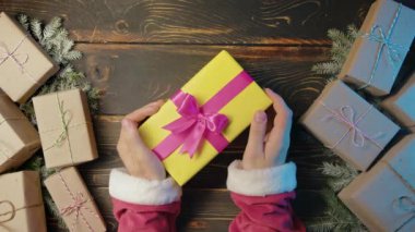 Noel Baba, erkek eli hediye kutusunu tahta masaya koyar. Sanatsal estetik, Noel zamanı. Üst manzara, şenlikli zemin. Görsel hikaye anlatımı. Yüksek kalite 4k görüntü