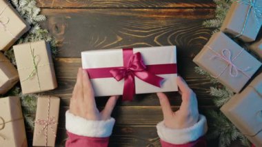 Noel Baba, erkek eli hediye kutusunu tahta masaya koyar. Sanatsal estetik, Noel zamanı. Üst manzara, şenlikli zemin. Görsel hikaye anlatımı. Yüksek kalite 4k görüntü