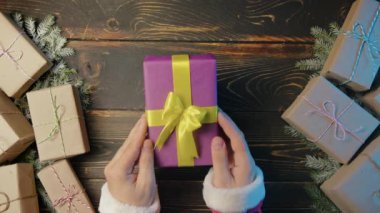 Noel Baba, erkek eli hediye kutusunu tahta masaya koyar. Sanatsal estetik, Noel zamanı. Üst manzara, şenlikli zemin. Görsel hikaye anlatımı. Yüksek kalite 4k görüntü