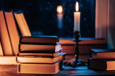 Ahşap pencere eşiğinde, mum ışığında yıkanmış bir yığın eski kağıt kitap. Sıcak bir sonbahar havası, yanan bir mum. Edebiyat terfileri ya da huzurlu görsel hikaye anlatımları. Yağmurlu sonbahar havası.