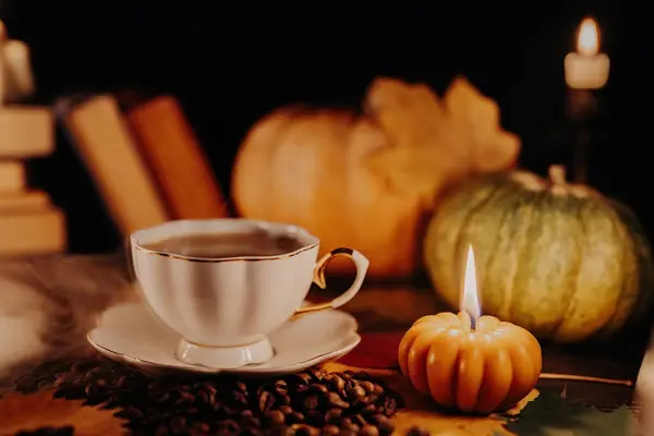 Porcelain coffee cup among pumpkin candles. Autumn-themed content, cafe promotions or visual storytelling that exudes comfort. Touch of intimacy, tranquil and inviting hygge atmosphere.