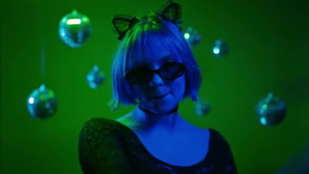 ネオンライトで頭を踊る若い美しい女性 ハロウィンパーティーのためのキティ猫の衣装 サングラスとレースの耳を持つセクシーなエレガントな女性 高品質の4K映像 — ストック動画