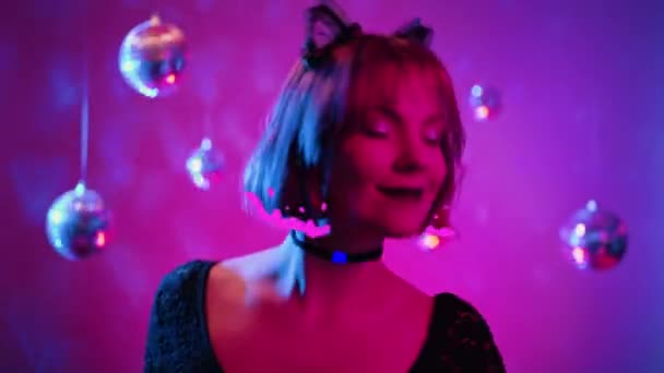 ネオンライトで頭を踊る若い美しい女性 ハロウィンパーティーのためのキティ猫の衣装 サングラスとレースの耳を持つセクシーなエレガントな女性 光るアニメーションファンクAiフィルターカメラ 高品質の4K映像 — ストック動画