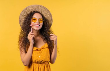 Young woman doing face massage with rose quartz stone roller on yellow background. Facial self care, beauty rituals, cosmetology, anti aging and anti-wrinkle treatment. High quality photo