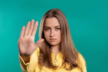 El işaretine hayır diyen ilgisiz bir kadın. İnkar etmek, reddetmek, katılmamak. Mavi arka planda genç bir kadının portresi, mola kavramı. Yüksek kalite