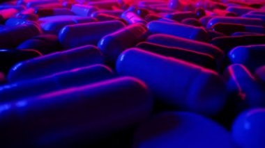 Renkli kapsül haplarının Macro sürgülü görüntüsü. Sağlık için farmasötik ilaç. Beslenme takviyeleri, faydalı vitamin konsepti. Neon ışığı, siyah arka plan. Yüksek kalite 4k görüntü